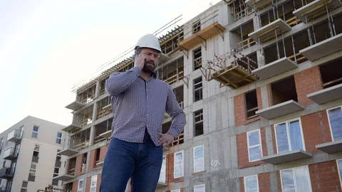 Construction manager talking by smarphone at builinding place. Slider shot. Vídeos de archivo 70804520