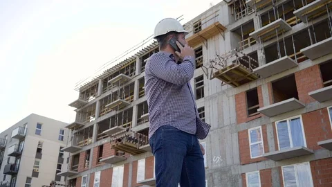 Construction manager talking by smartphone at building place. Slider shot. Vídeos de archivo 70804568