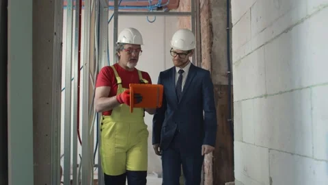 Construction manager with worker checking on site using tablet Stock Footage 133638464