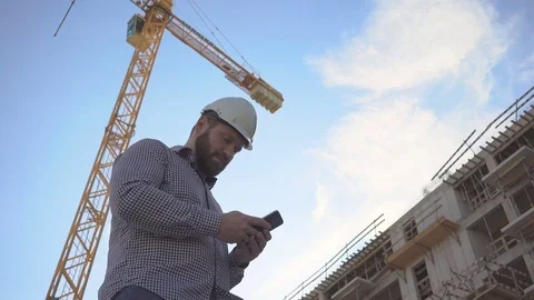 Construction manager writing message on smartphone at building place. 库存影片 70804644