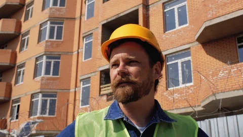 Construction manager in a yellow helmet with a beard and mustache speaks. 4k Stock Footage 106019882