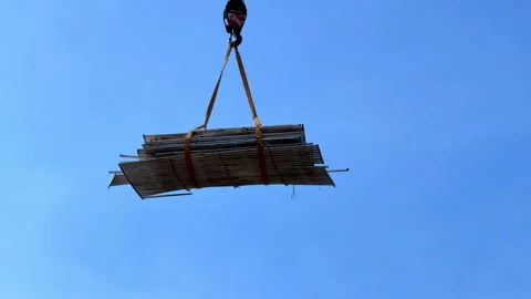 Construction material bundle lifted by crane against blue sky Stock Footage 337402429