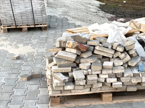 Construction materials are piled up on a paved surface at a building site, .. Stockfoto's