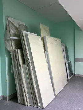 Construction materials are stacked against a green wall in a building space Stock Photos
