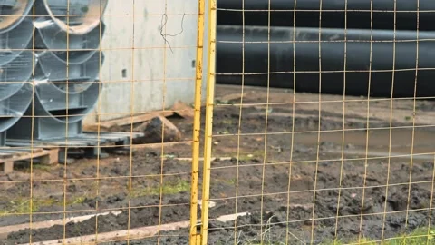 Construction materials are stacked neatly behind a yellow fence at a Видео 344676028