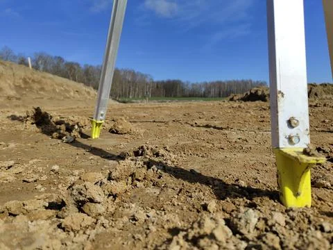 Construction measurement tools in muddy rural field with clear blue sky and t Stock Photos