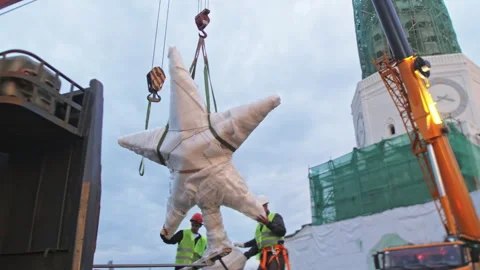 Construction men fix wrapped star on crane with ropes near tower Vídeo Stock 258468400