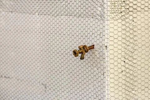 Construction mesh stretched over foam near a corner on a wall with a spigot Stock Photos