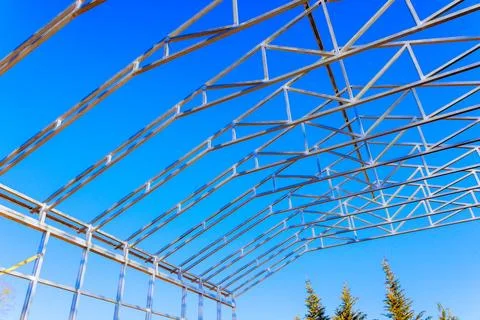 Construction of a metal frame structure under a clear blue sky in a rural area Stock Photos