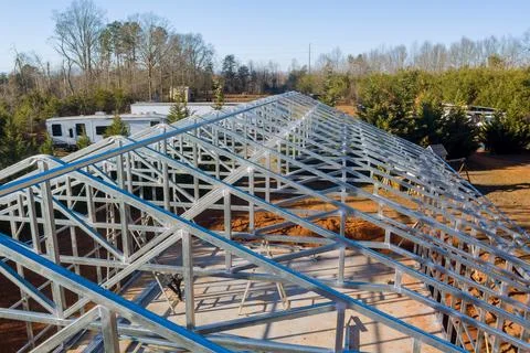 Construction of a metal structure progresses under clear skies in a rural area Stock Photos