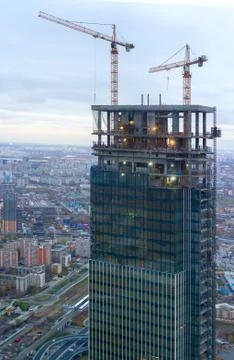The construction of a modern skyscraper. Tower crane at construction site in Stock Photos