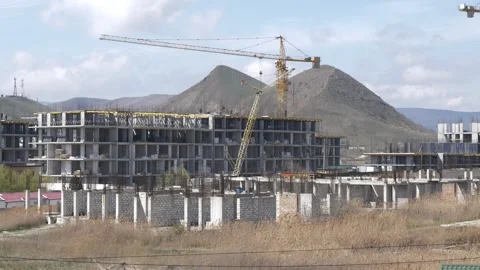 Construction of monolithic buildings against the backdrop of high hills Stock Footage 241564712