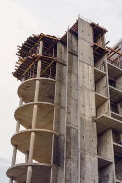Construction of a monolithic concrete building gray sky on the background Stock Photos