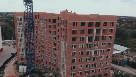 Construction of a multi-storey brick residential building of red color next to Stock Footage 126002250