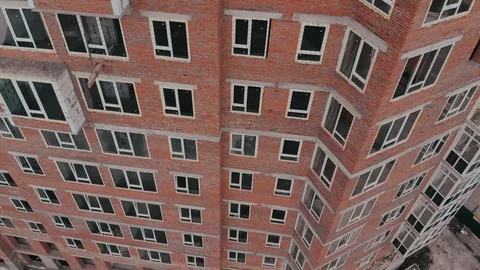 Construction of a multi-storey brick residential building of red color next to Stock Footage 126002336
