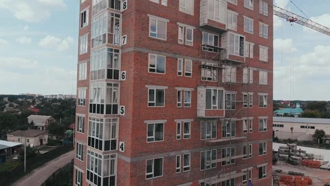 Construction of a multi-storey brick residential building of red color next to Stock Footage 126002381