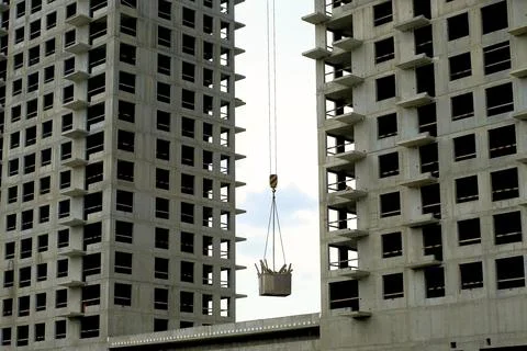 Construction of a multi-storey building, a crane lifts the load Stock Photos