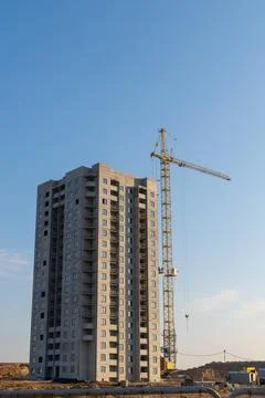 Construction of a multi-storey building with a crane against the blue sky. 写真素材