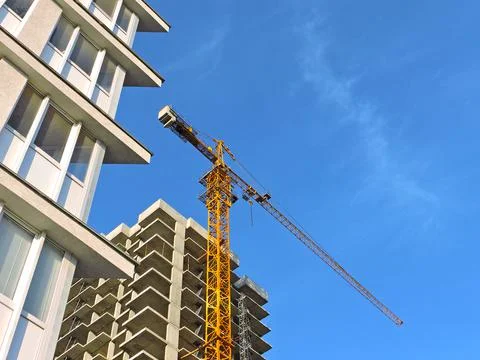 Construction of a multi-storey building with a yellow crane on a blue sky Stock Photos