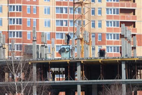Construction of multi-storey monolithic house and workman builder on backgrou Stock Photos