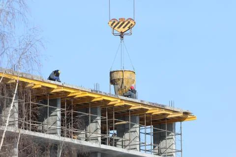 Construction of multi-storey monolithic house and workers builders on backgro Stock Photos