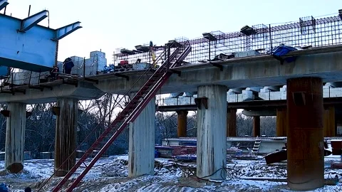 Construction of a new automobile bridge across the river, on a sunny winter d Stock Footage 320998048