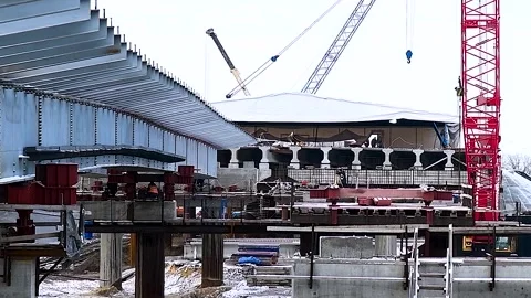 Construction of a new automobile bridge across the river, on a sunny winter d Stock Footage 320998073
