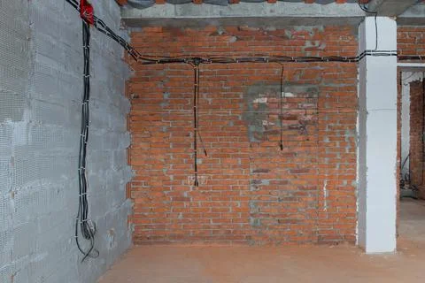 Construction of a new house, electrical cables laid out on the brick walls ac Stock Photos