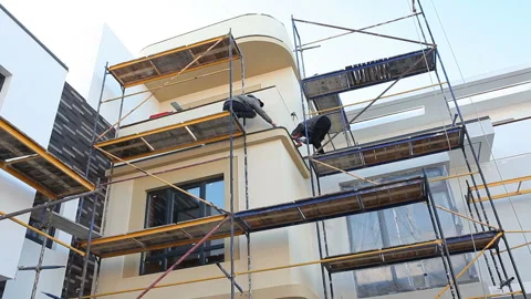 Construction of a new house.Two workers make the facade of house on scaffolding Stock Footage 221688107
