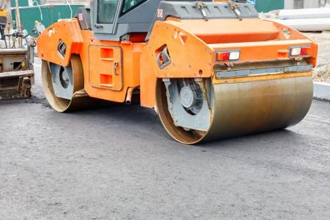 Construction of a new road. A large vibratory road roller paired with an asph Stock Photos