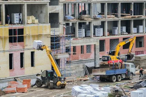 Construction of a new school. Builders and workers construct a building, a lo Stock Photos