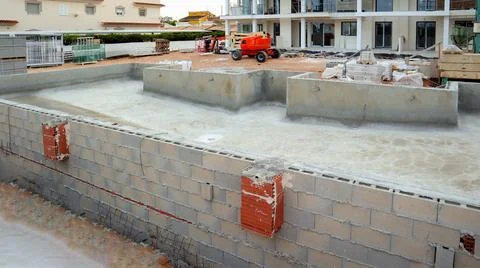 Construction of a new swimming pool adjacent to a house under development i.. Stock Photos