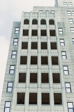 Construction is ongoing on a tall building with vacant windows. The structure 写真素材