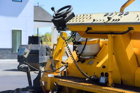 Construction paving machine is parked next to building site, tools are on das Stock Photos