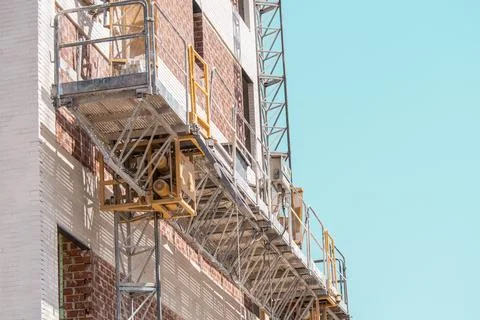 A construction platform or lift-elevator is attached to a brick building Stock Photos