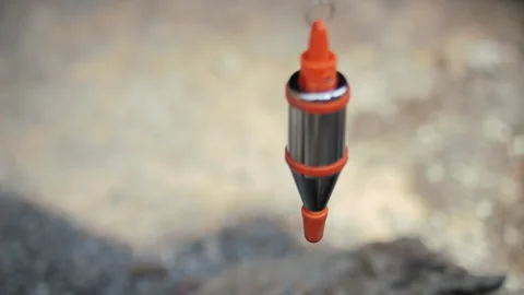 Construction plumb bob hanging above rough concrete ground Stock Footage 310406642