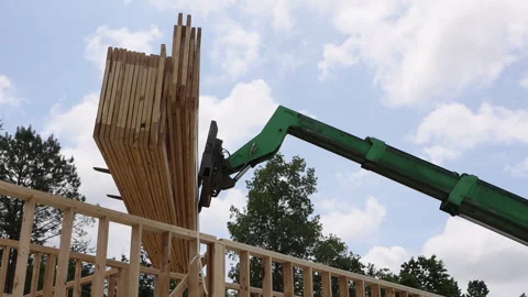 Construction process at building site with telehandler machinery lifting wooden Stock Footage 309787037