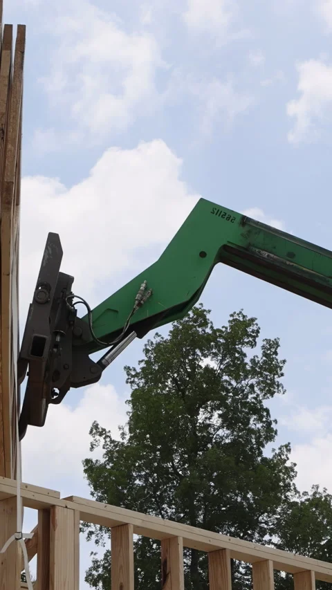 Construction process at building site with telehandler machinery lifting wooden Stock Footage 320626398