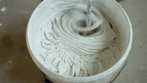 Construction process. Putty diluted with water in bucket is mixed with power Stock Footage 322730925
