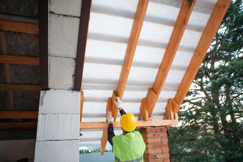 Construction process shows carpenter preparing to fit roof batten across ti.. Stock Photos