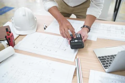 Construction Professional Using Calculator on Architectural Plans for Proje.. Stock Photos