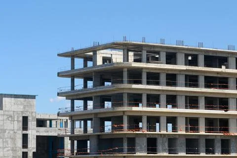 Construction progresses on a modern multi-story building under a bright blu.. Stock Photos