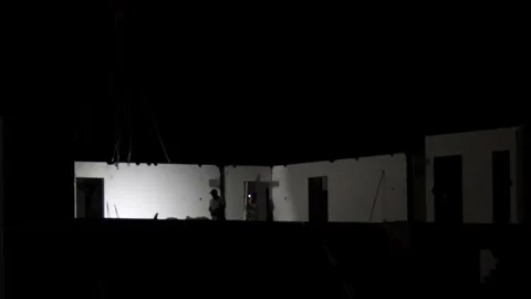 Construction project at night, heavy duty crane lifts large precast wall section Stock Footage 323912224