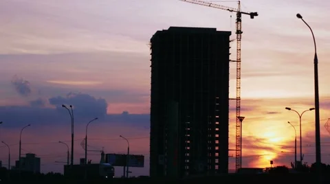 Construction project silhouette against sunset sky. City landscape with cars and Stock Footage 66454942