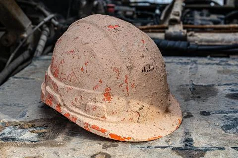 Construction protective helmet covered with mud and drilling mud. Concept Stock Photos