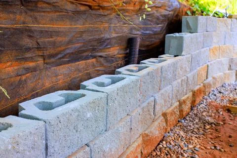 Construction of retaining wall using gray concrete blocks in backyard setting Stock-Fotos