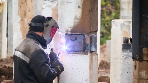 Construction of the road. A worker in a special mask solder a metal part to the Stock-Footage 95188593