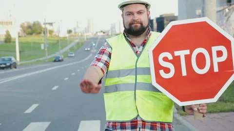 A construction road worker stopping traffic, holding a stop sign. Video stock 90844476