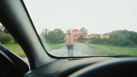 A construction road worker stopping traffic, holding a stop sign. View from the Stock Footage 90844691