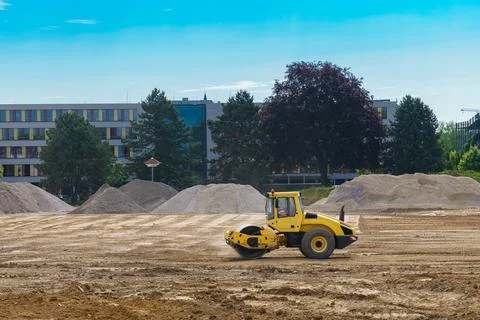 A construction roller spreads out the ground at a construction site. Stock Photos
